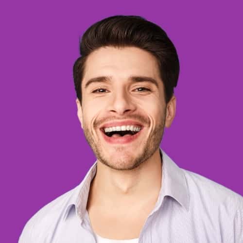 Male smiling with black hair and beard with purple background.