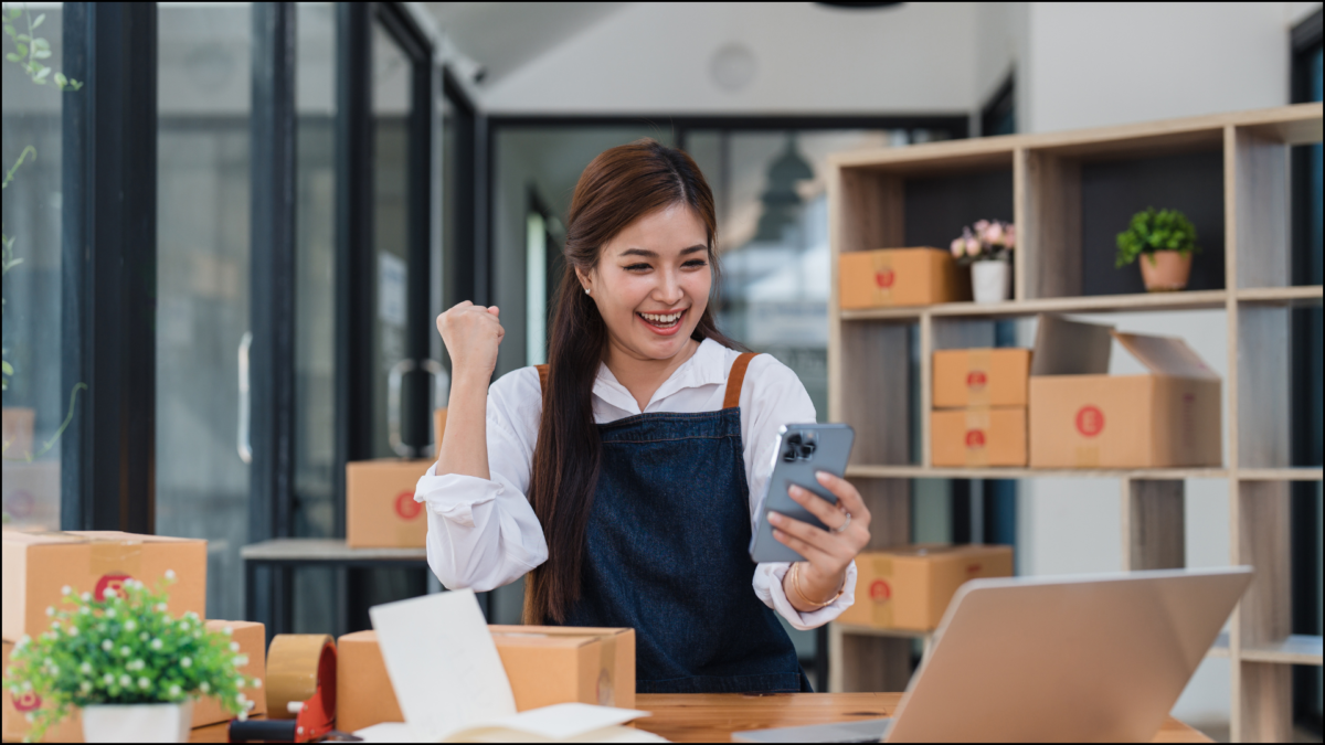 Business women surrounded by boxes fist pumping success